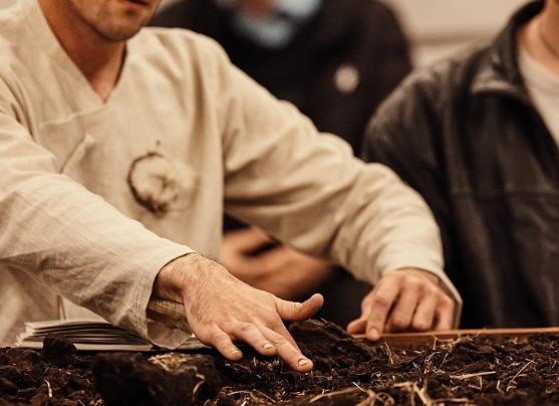 A man sitting at a table with his hands in soil